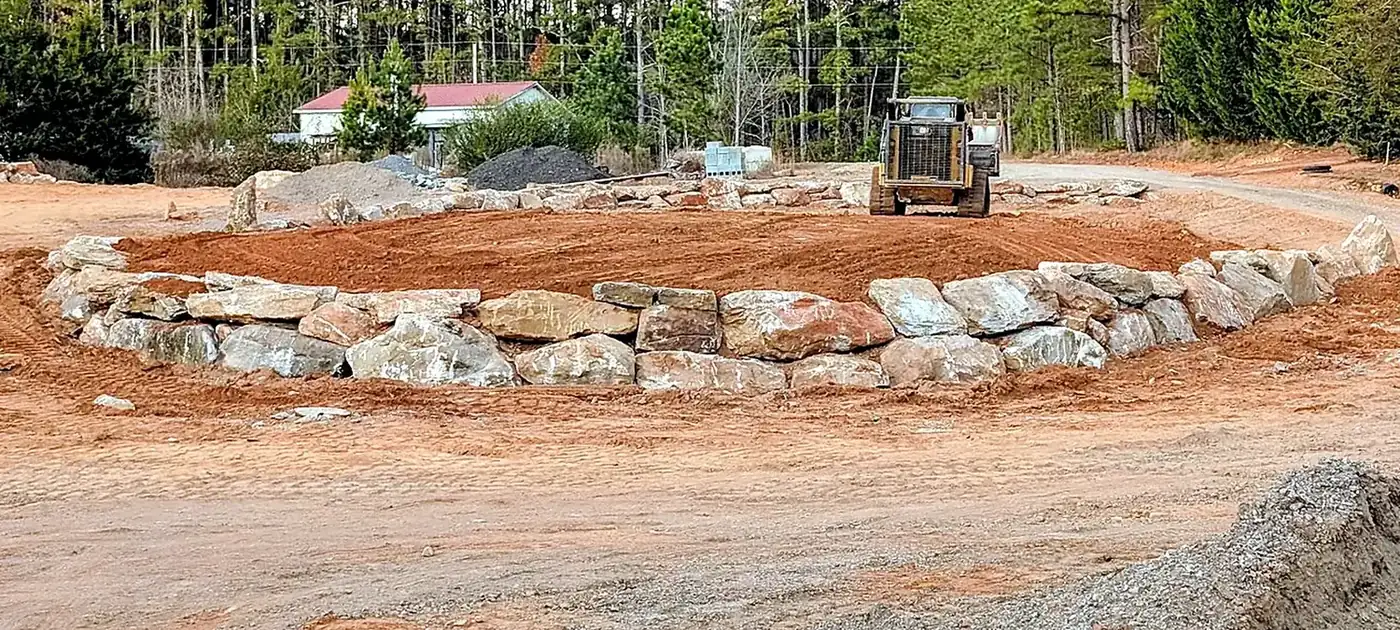 Large natural stone retaining feature shaped into a graded site services by 3 George's Grading