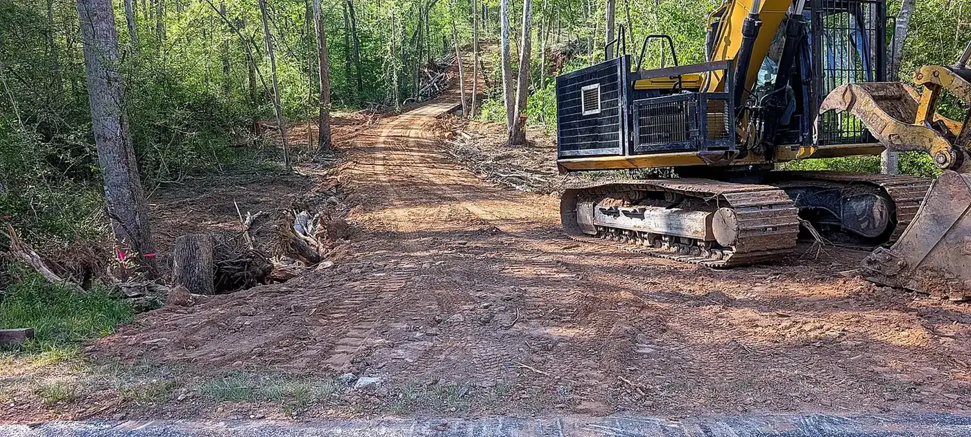 Excavator preparing and widening a private wooded access road services by 3 George's Grading