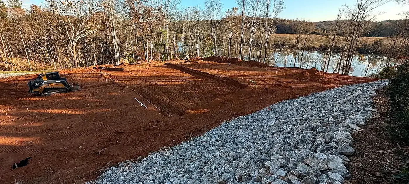 Finished red-clay building site with stabilized stone edge services by 3 George's Grading